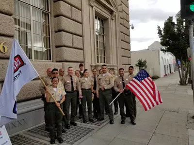 Sheriff Villanueva pictured next to deputies holding up flags