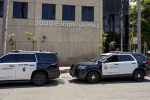 picture of two black and white Sheriff vehicles parked infront of the Transit Service's station. The building is tan marble with large address "2000 East Imperial Hwy."