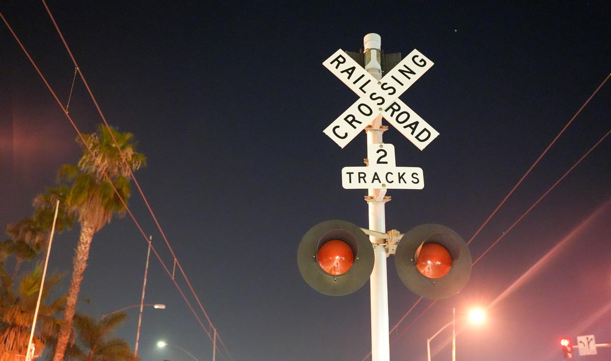 picture of a night sky, the Rail Road sign is centered near a rail road crossing.