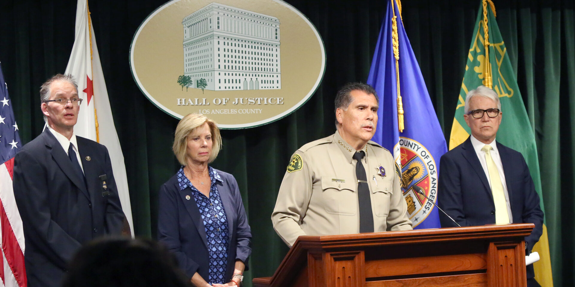 Sheriff Luna at a poduim with District Attorney Gascon, and Supervisor Janice Hanh in the background