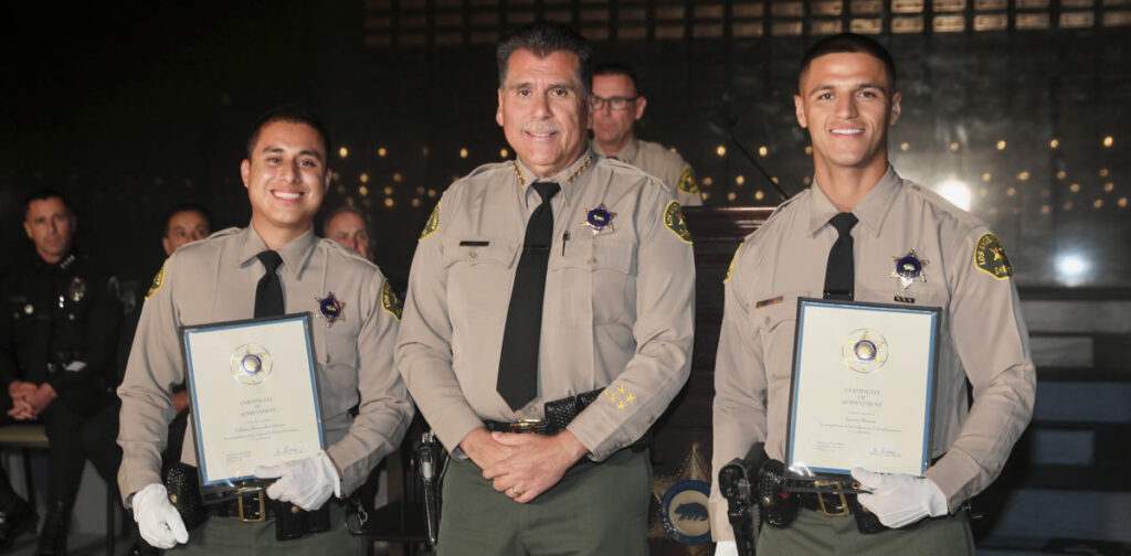 picture of Sheriff luna in the center of two deputies getting rewards. Rivera is on the left of Sheriff luna, and Gomez is on Sheriff Luna's right.