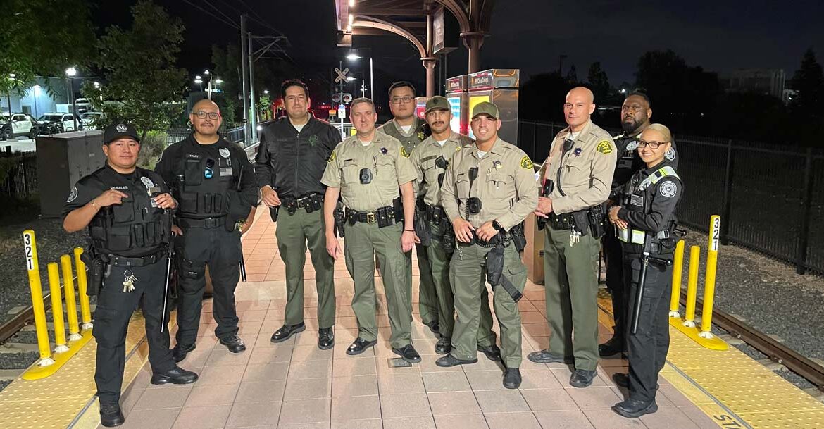 Group of Deptuies pose for pictures with Metro Security on metro platform.