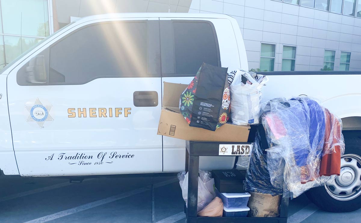 White truck parked with a cart of donations next to it. Sheriff logo is on the door.