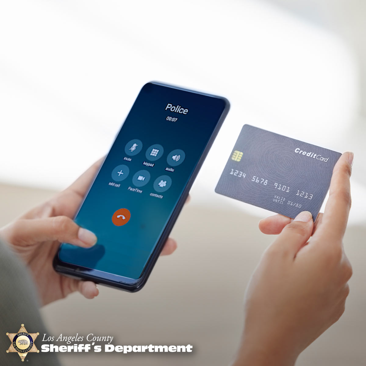 Person holding a cell phone; caller ID on screen says "Police"; the person is holding a credit card in their other hand